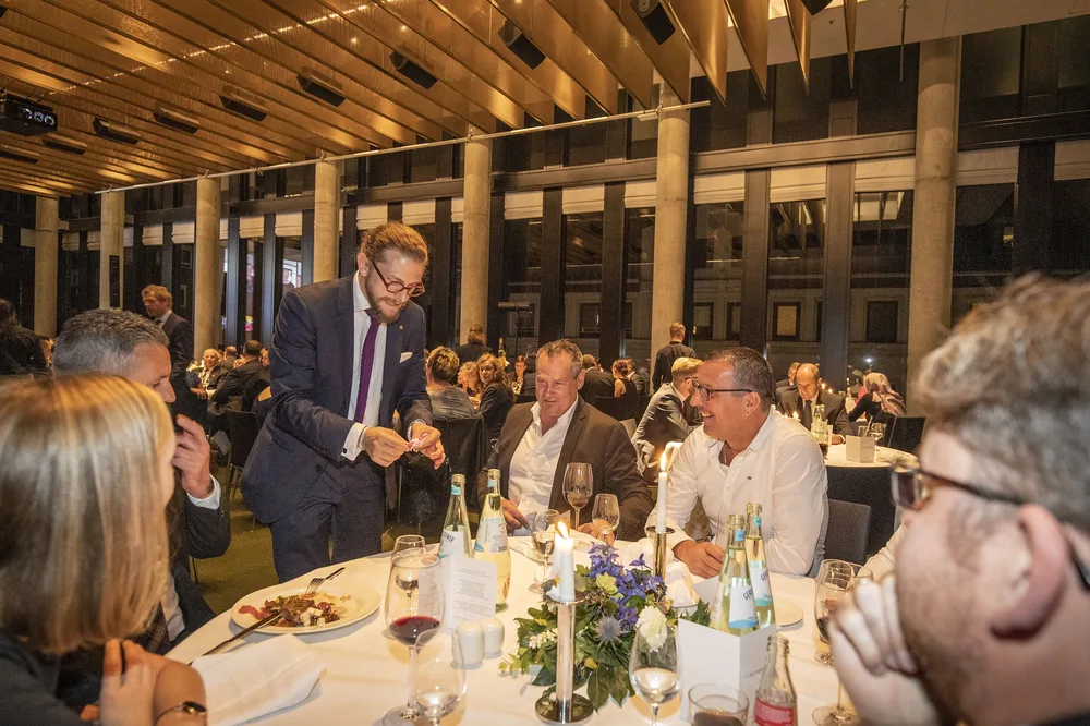 Close-Up am festlichen Dinnertisch: Simabu zeigt den Gästen eine Karte im Kerzenschein