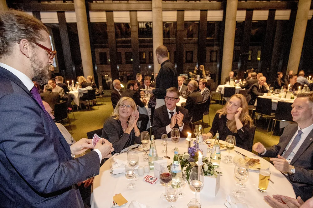 Tischzauberei beim Gala-Dinner: Zauberer Simabu am festlich gedeckten Tisch, Gäste applaudieren