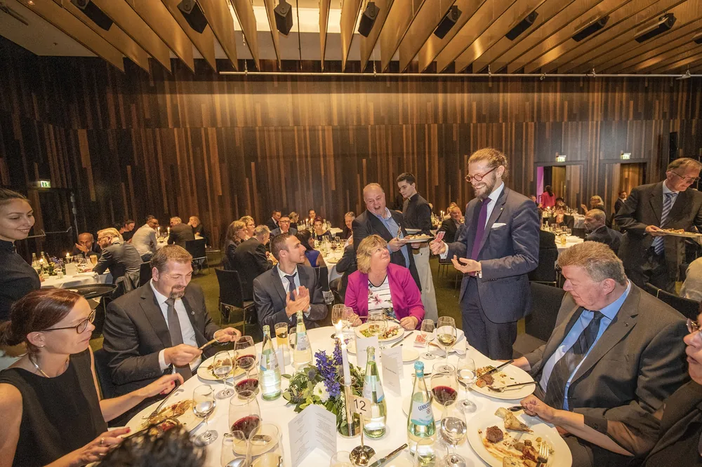 Zauberer Simabu zwischen den runden Tischen eines Gala-Dinners – Close-Up im Saal