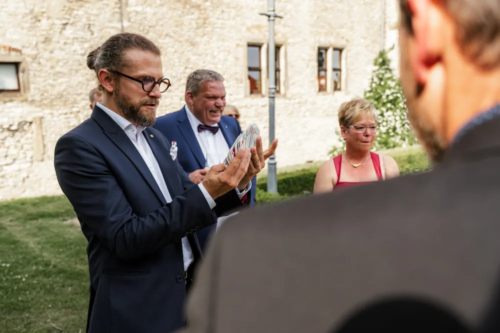 Sektempfang bei der Hochzeit: Zauberer Simabu mit Karten zwischen den Gästen im Garten